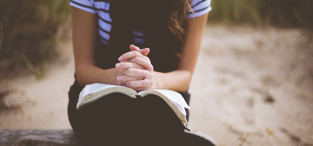 woman sitting on brown bench while reading book