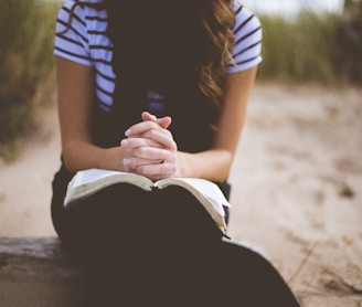 woman sitting on brown bench while reading book