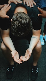 man sitting on chair holding and surrounded by people