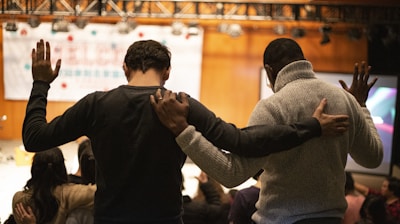two men holding ear others hand