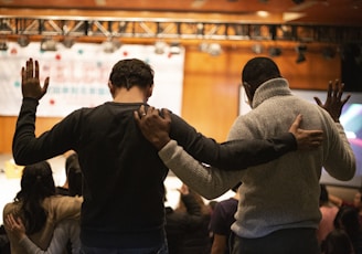 two men holding ear others hand